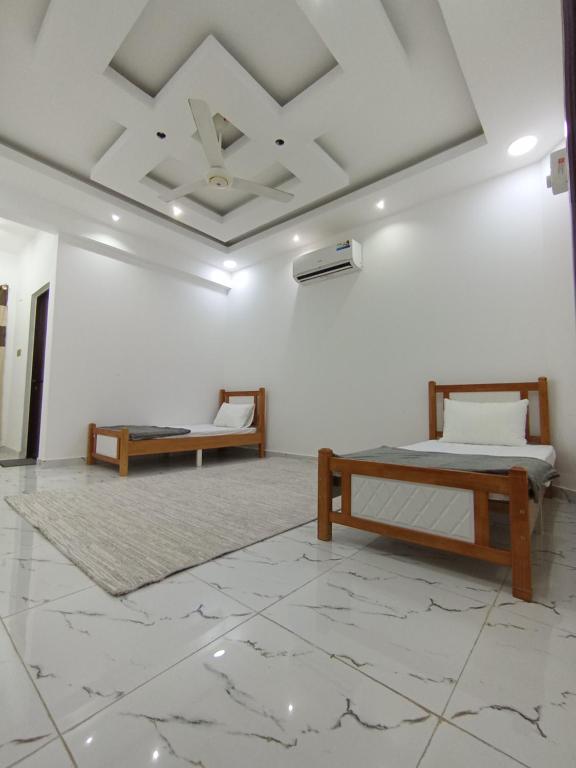 2 Betten in einem Zimmer mit einer weißen Wand in der Unterkunft شقة المعبيلة الجنوبية in Ghursheba