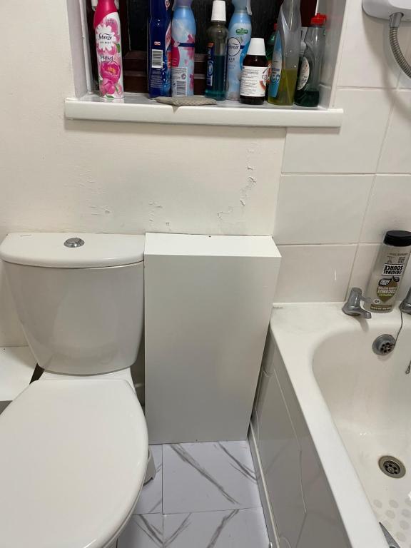 a white bathroom with a toilet and a bath tub at High View in Swindon