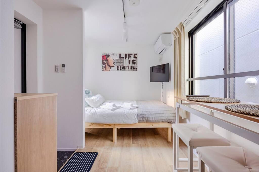 um quarto branco com uma cama e uma janela em アンドステイ池袋4丁目 em Tóquio