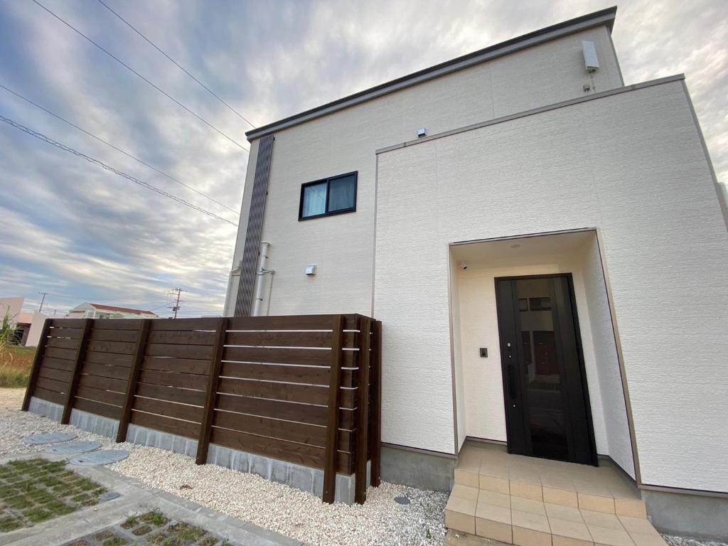 un edificio bianco con una porta e una recinzione di Rs Stay Villa MIYAKO B a Miyakojima