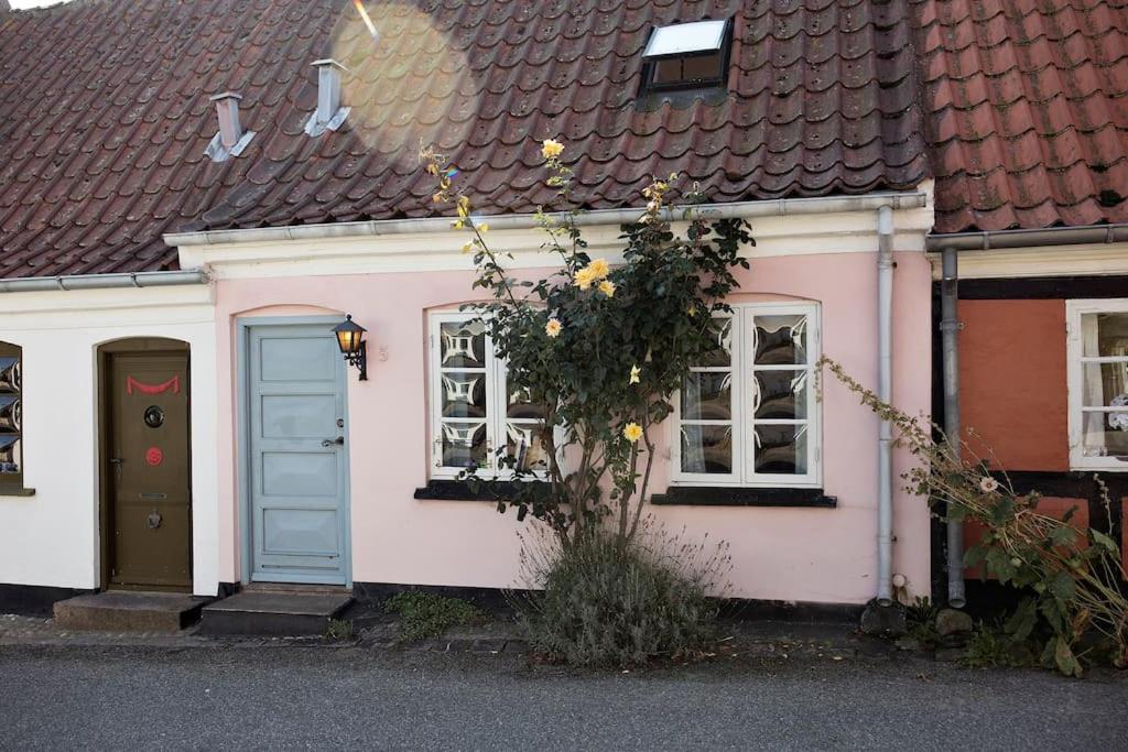 różowo-biały dom z niebieskimi drzwiami w obiekcie Skønt fiskerhus. Tæt på by, havn og havet w mieście Marstal