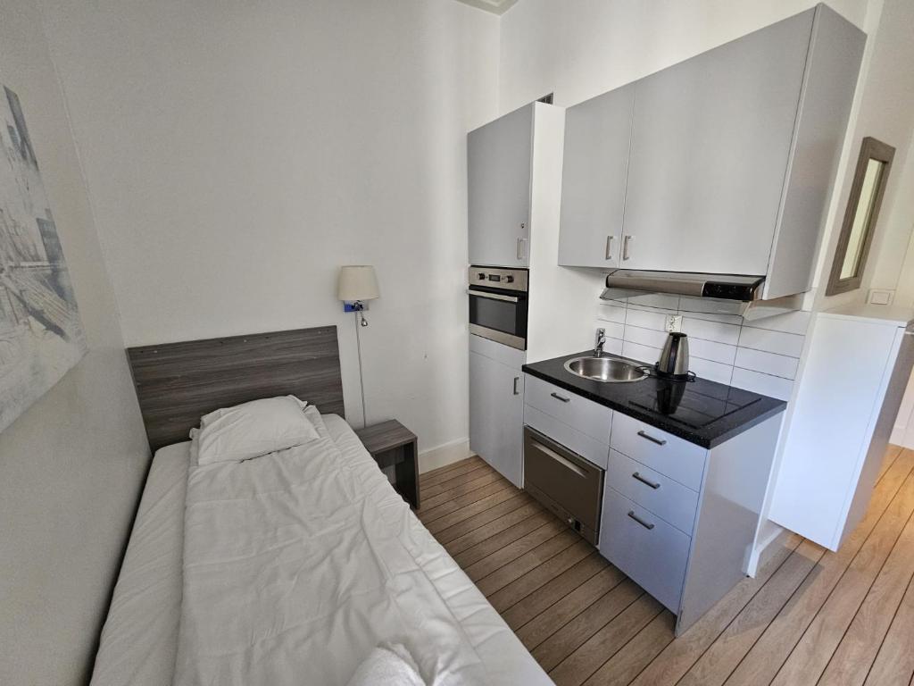 uma pequena cozinha com uma cama e um lavatório em Parkveien Comfy Studios em Oslo