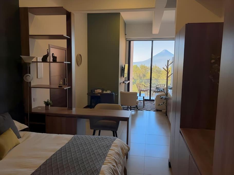 a bedroom with a bed and a desk with a view at Urban Gem: Comfort, Style, Views. Apartment close to the AIRPORT in Guatemala