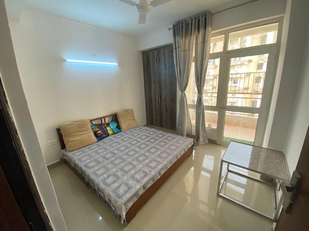 1 dormitorio con cama y ventana grande en home away from home, en Greater Noida