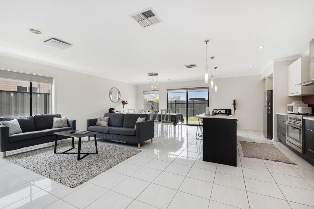 a living room with two couches and a kitchen at Modern 4BR house perfect for family getaway in Point Cook