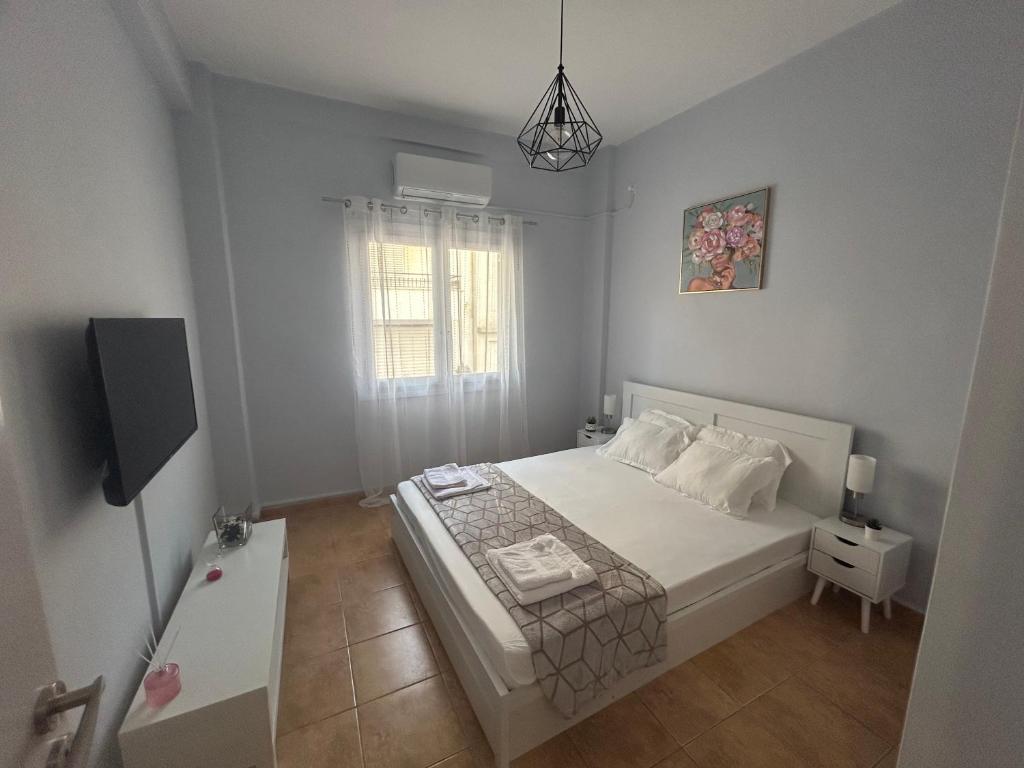 1 dormitorio con cama blanca y ventana en ΑKTIS apartment 2 near airport, en Artemida