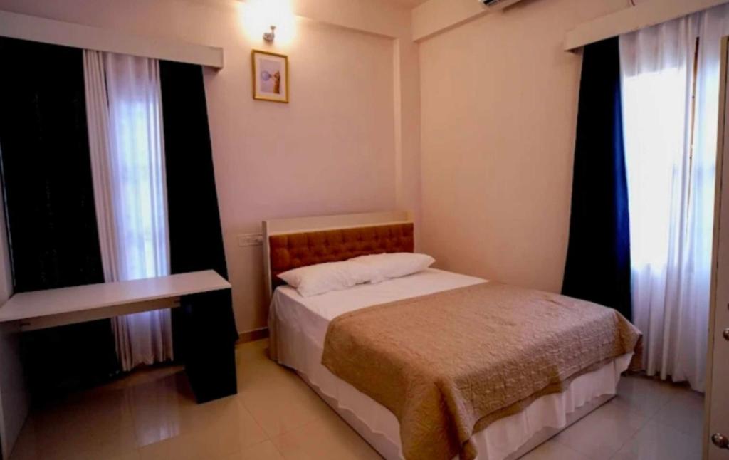 a small bedroom with a bed and two windows at OYO Kailath Safe Stay Tourist Home in Thekkady