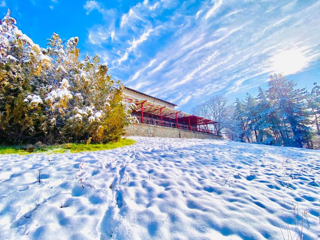 um campo coberto de neve com um edifício ao fundo em Хижа Манастирчето-Книжовник em Haskovo