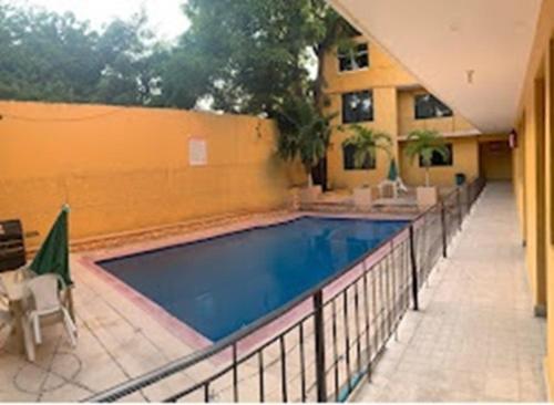 a swimming pool next to a building with a yellow wall at HOTEL PALACIO in Acapulco