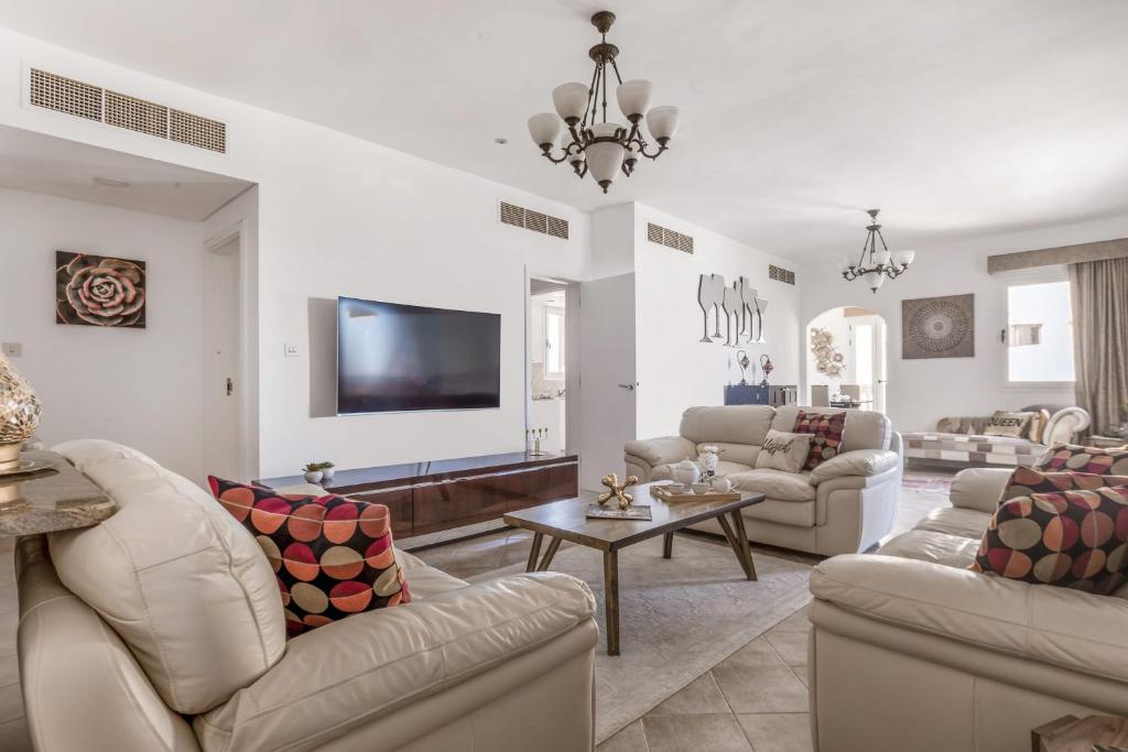 Frank Porter - Al Badia 2 في دبي: غرفة معيشة بأثاث أبيض وتلفزيون بشاشة مسطحة