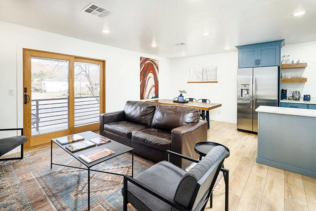 a living room with a leather couch and a kitchen at Near Downtown Stylish 2BR With Amazing Patio - #2 in Moab