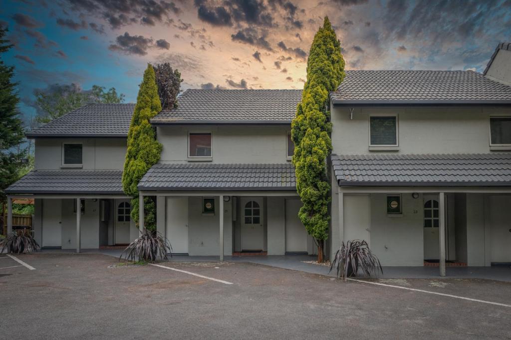 ein Gebäude mit zwei Bäumen auf einem Parkplatz in der Unterkunft Elphin Serviced Apartments in Launceston