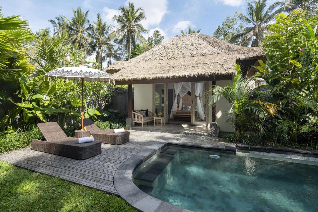 a villa with a swimming pool and a hut at Granary Villas Ubud in Tegalalang