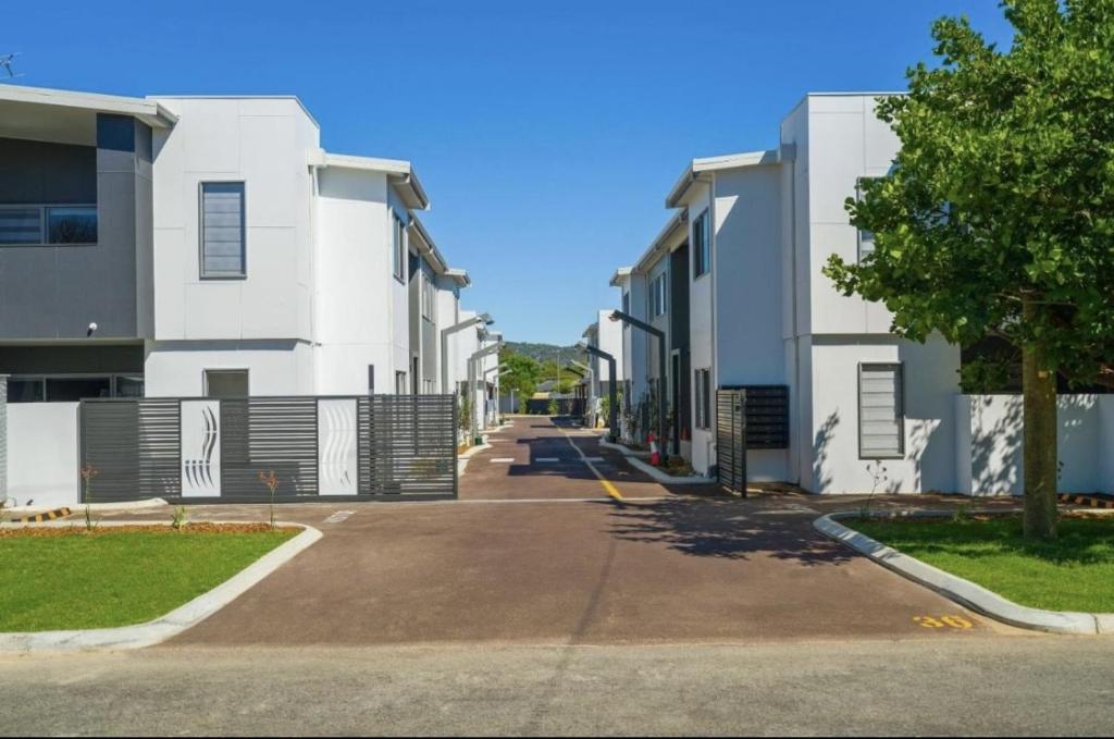 an empty street in front of white buildings at Modern Hillside Apartments in Kelmscott