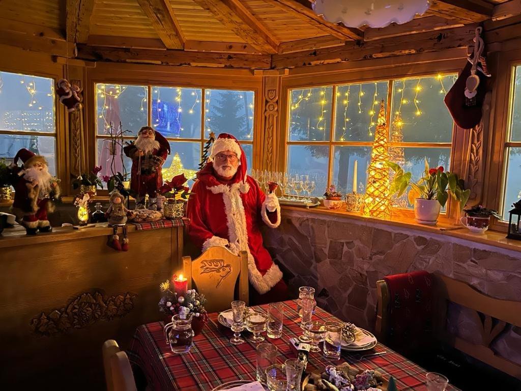 une clause de santa assise à une table dans un restaurant dans l'établissement The Post Stana de Vale, à Stâna de Vale
