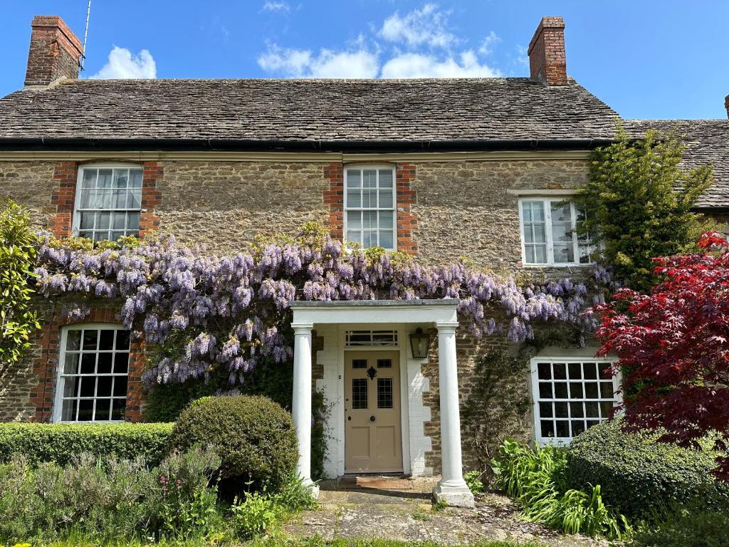 una casa de ladrillo con flores púrpuras en la pared en Reynolds House en Faringdon