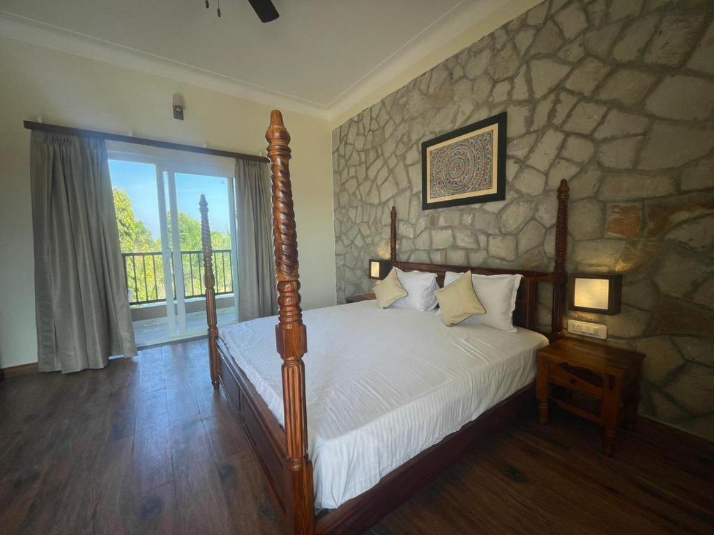 1 dormitorio con cama y pared de piedra en Tiger Retreat, en Sawāi Mādhopur