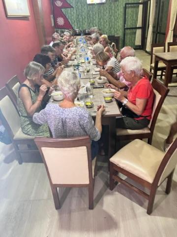 un grupo de personas sentadas en una mesa larga en Hotel Suramma Pvt. Ltd., en Rummindei