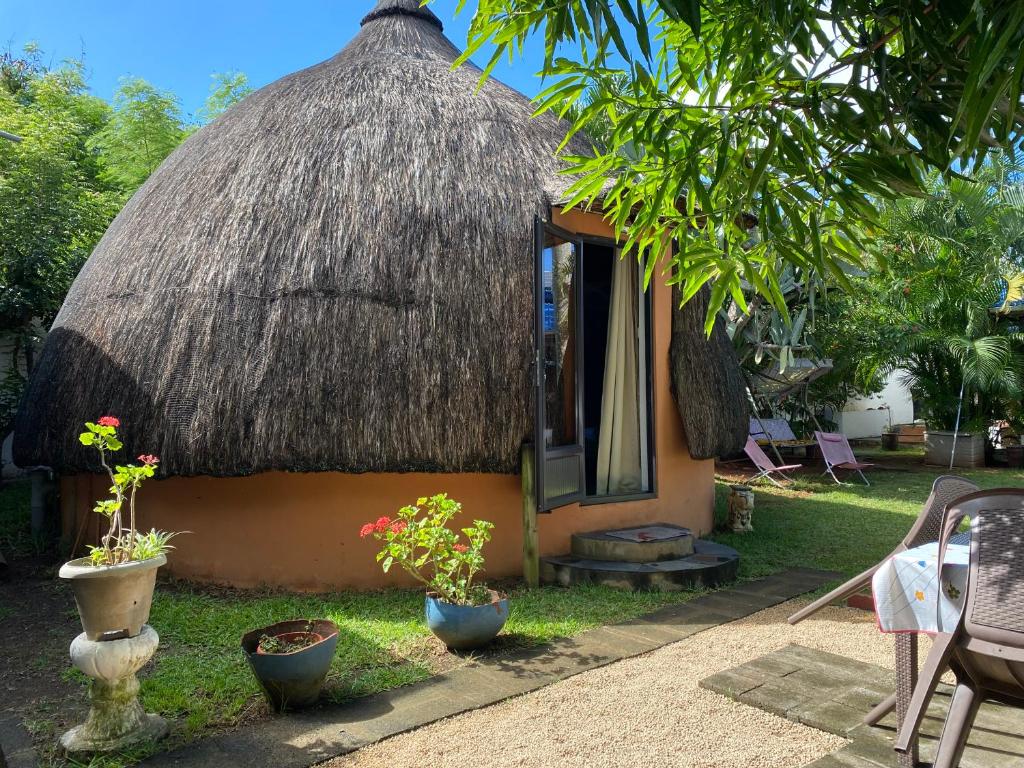 a small house with a thatched roof and some plants at Cazhibiscus in Trou aux Biches