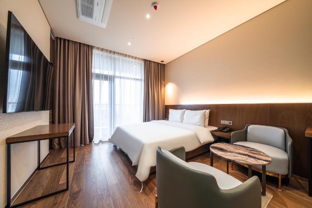 une chambre d'hôtel avec un lit, une table et des chaises dans l'établissement Uiwang Milos Hotel, à Uiwang