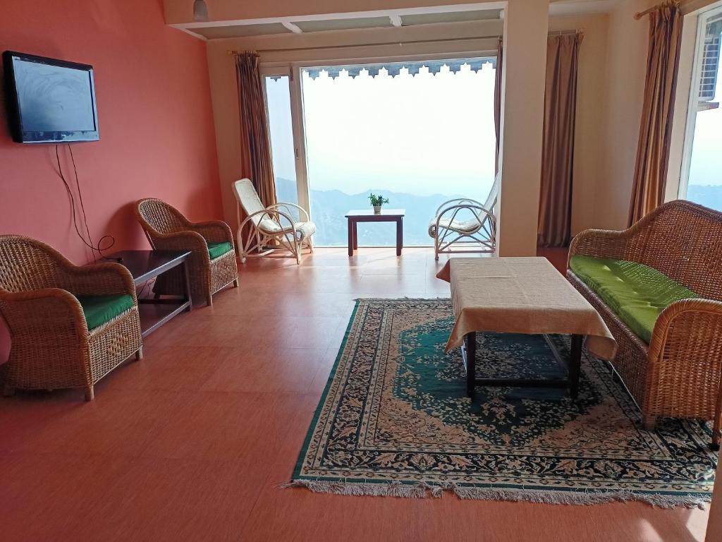 a living room with chairs and a table and a tv at Beechwood Holiday Apartments in Mussoorie