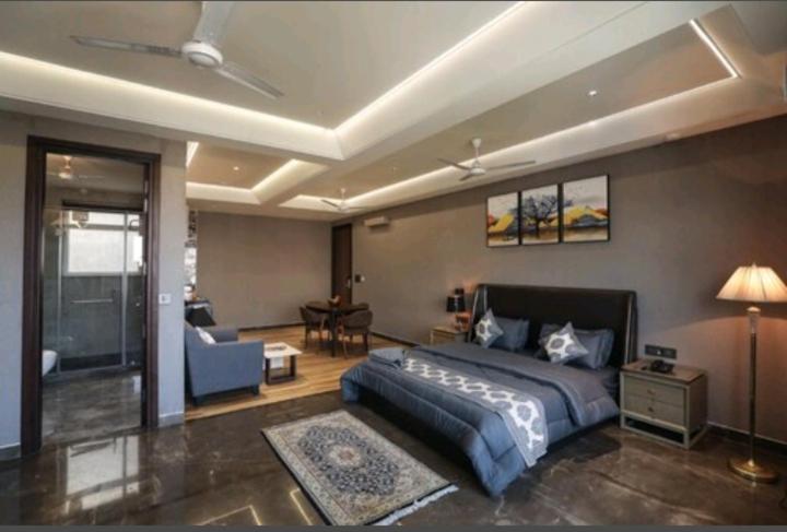 ein Schlafzimmer mit einem Bett und ein Wohnzimmer in der Unterkunft KRYC Luxury Living in Neu-Delhi