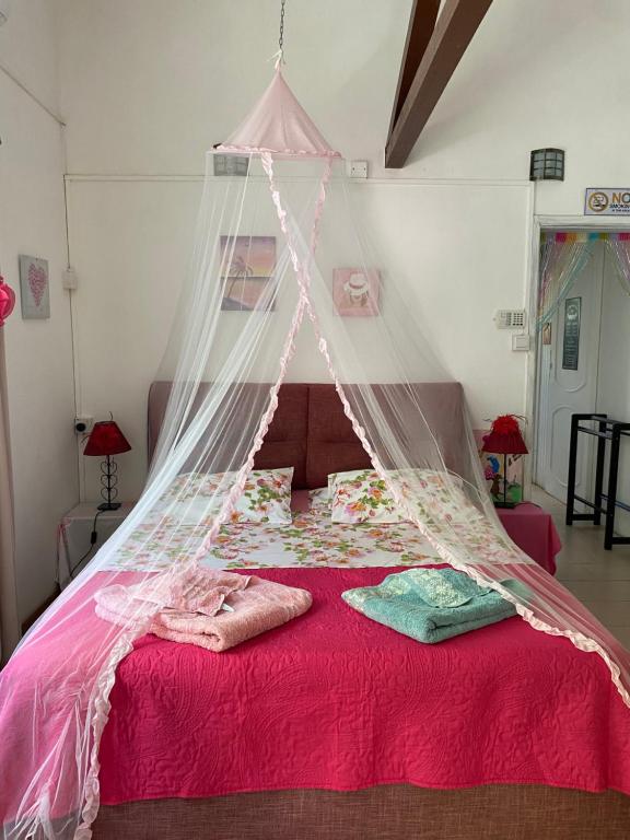 a bedroom with a canopy bed with red sheets at Chambre D'hote PLACE DES AMOUREUX in Trou aux Biches