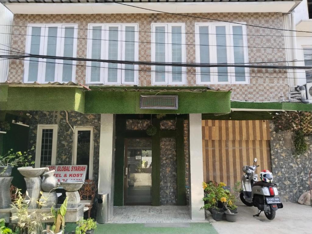 雅加達的住宿－Hotel Global Syariah，前面有一辆摩托车停放的房子