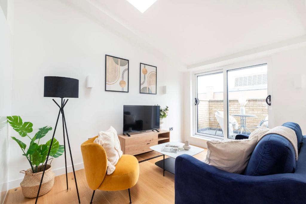 a living room with a blue couch and a tv at Fitzrovia & Soho with Balcony - CityApartmentStay in London