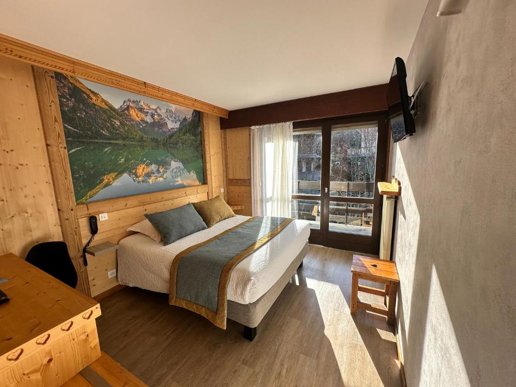 a bedroom with a bed and a large window at Hotel Le Soly in Morzine