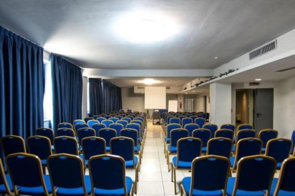 pusty pokój z niebieskimi krzesłami i zasłonami w obiekcie Blu Hotel - Sure Hotel Collection by Best Western w mieście Collegno
