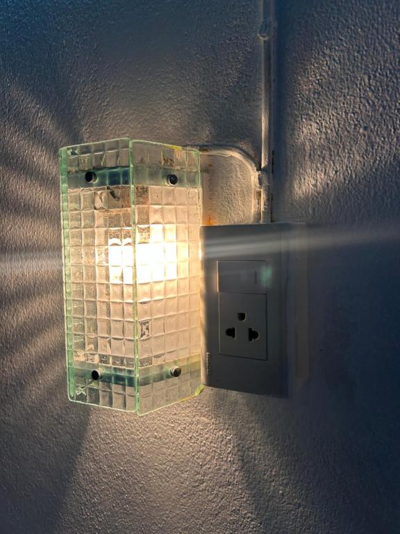 a lightswitch on a wall with a light on it at Just sleep in Ban Mo Nae