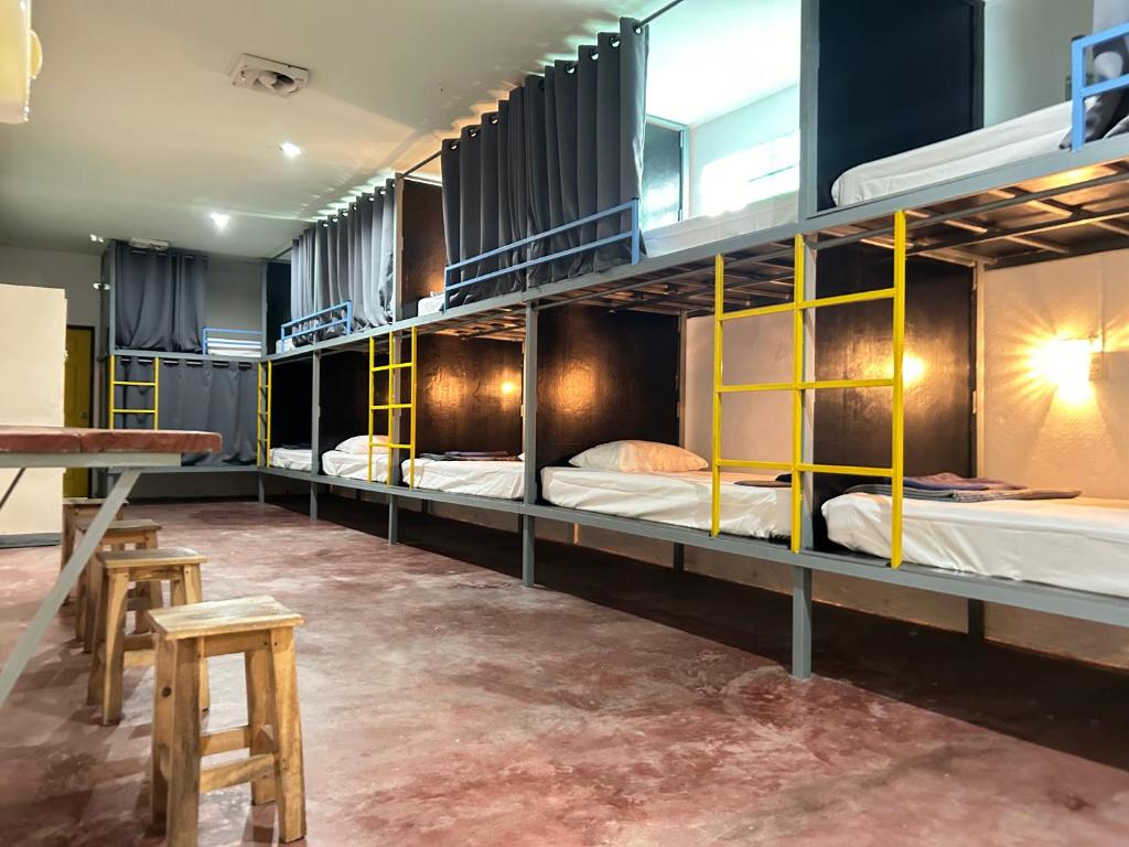 a room with four bunk beds with a table and stool at Just sleep in Ban Mo Nae