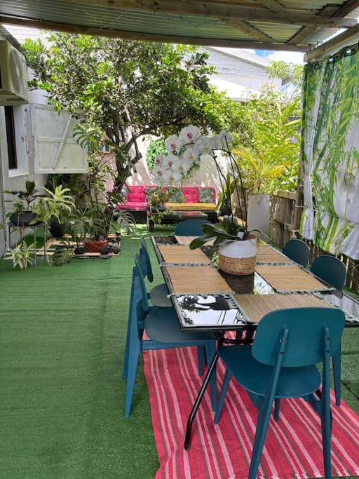 une table et des chaises sur une terrasse agrémentée de plantes dans l&#39;établissement Ptite case Fantaisie, à Saint-André