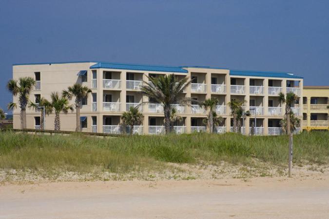 un grand bâtiment avec des palmiers devant lui dans l'établissement Oceanview Lodge - Saint Augustine, à Saint Augustine