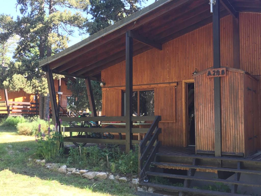 uma grande cabana de madeira com um alpendre e uma porta em Chalet mitoyen pres des pistes em Bolquère - Pyrénées 2000