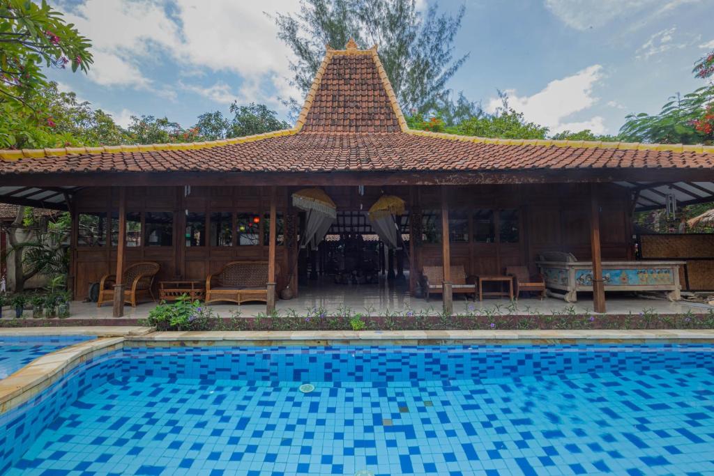 a house with a swimming pool in front of it at Omah Gili Hotel in Gili Air