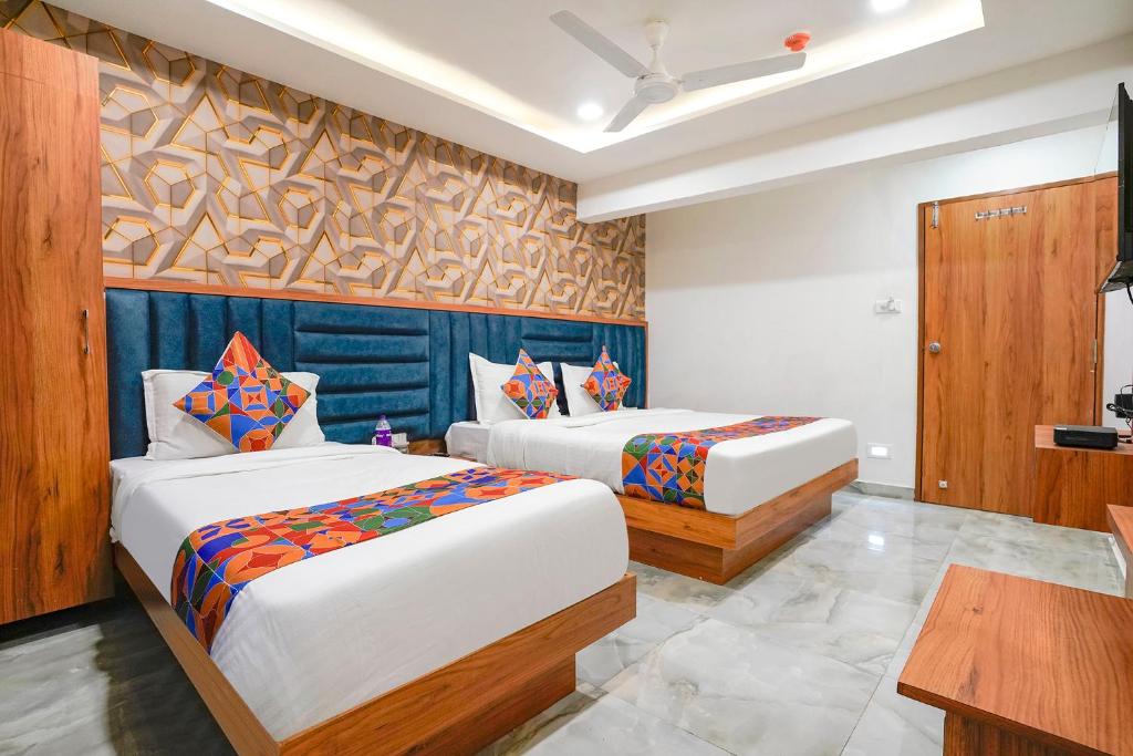 a bedroom with two beds and a table at FabHotel Nobel Inn in Ahmedabad