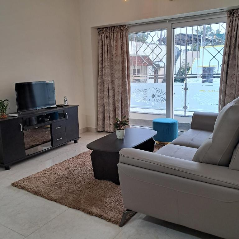 a living room with a couch and a tv at Yazh Vedha Homes in Chennai