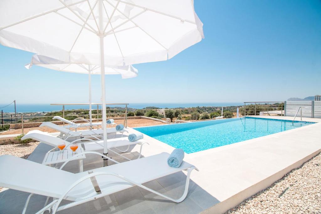 a villa with a pool and chairs and an umbrella at Francis & Gregorys Luxury Villas in Afantou