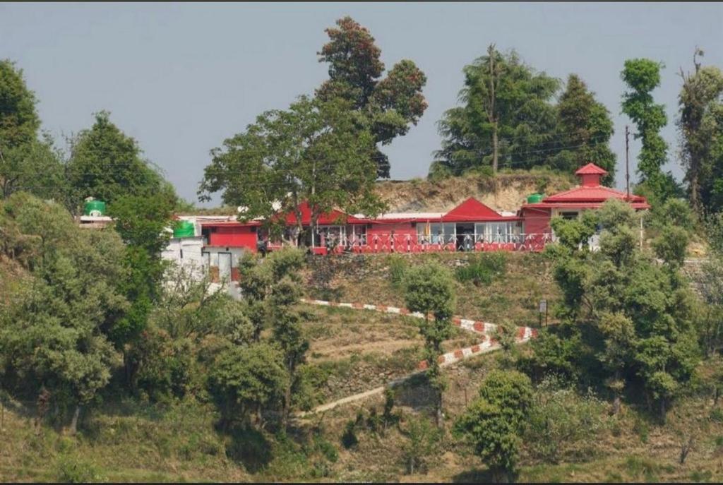 una casa roja en la cima de una colina en Bagheecha Homestay, en Kanatal