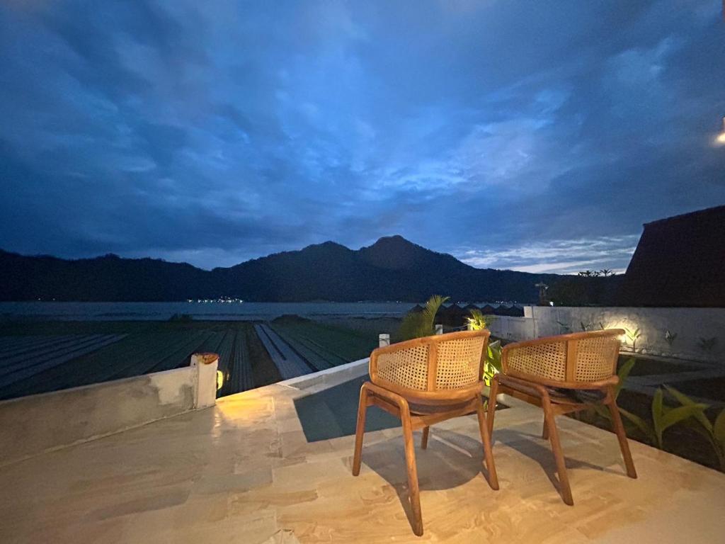 two chairs on a balcony with a view of a field at La vida Bali in Kubupenlokan