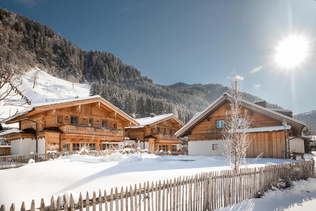 a log cabin in the snow with a fence at Birnbaum Chalets Grossarl in Grossarl