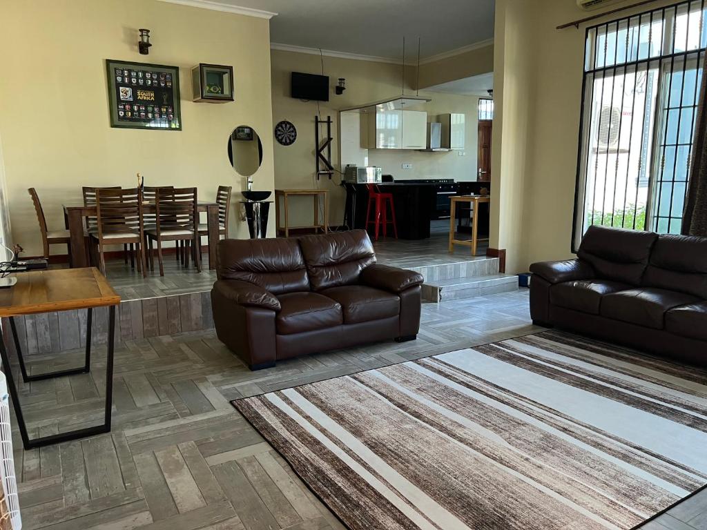 sala de estar con 2 sofás de cuero y comedor en RK Residence, en Dar es Salaam