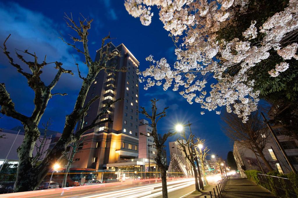 una strada di città di notte con un palazzo alto di Kokusai 21 International Hotel a Nagano