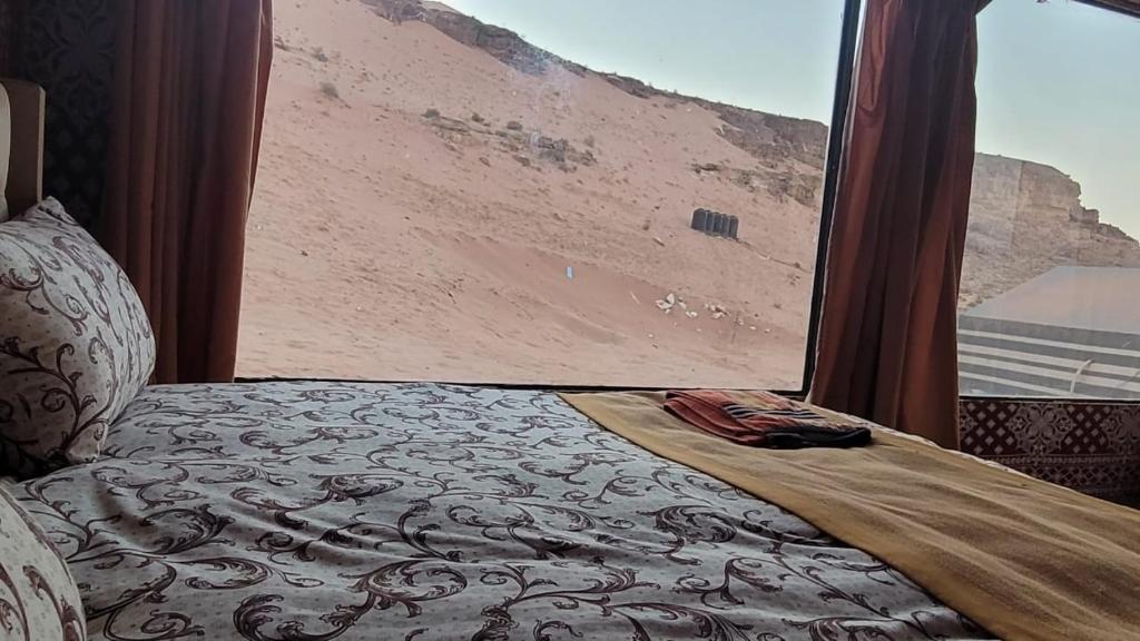 a bed in a room with a view of a desert at Rum Grand Tours Camp in Disah