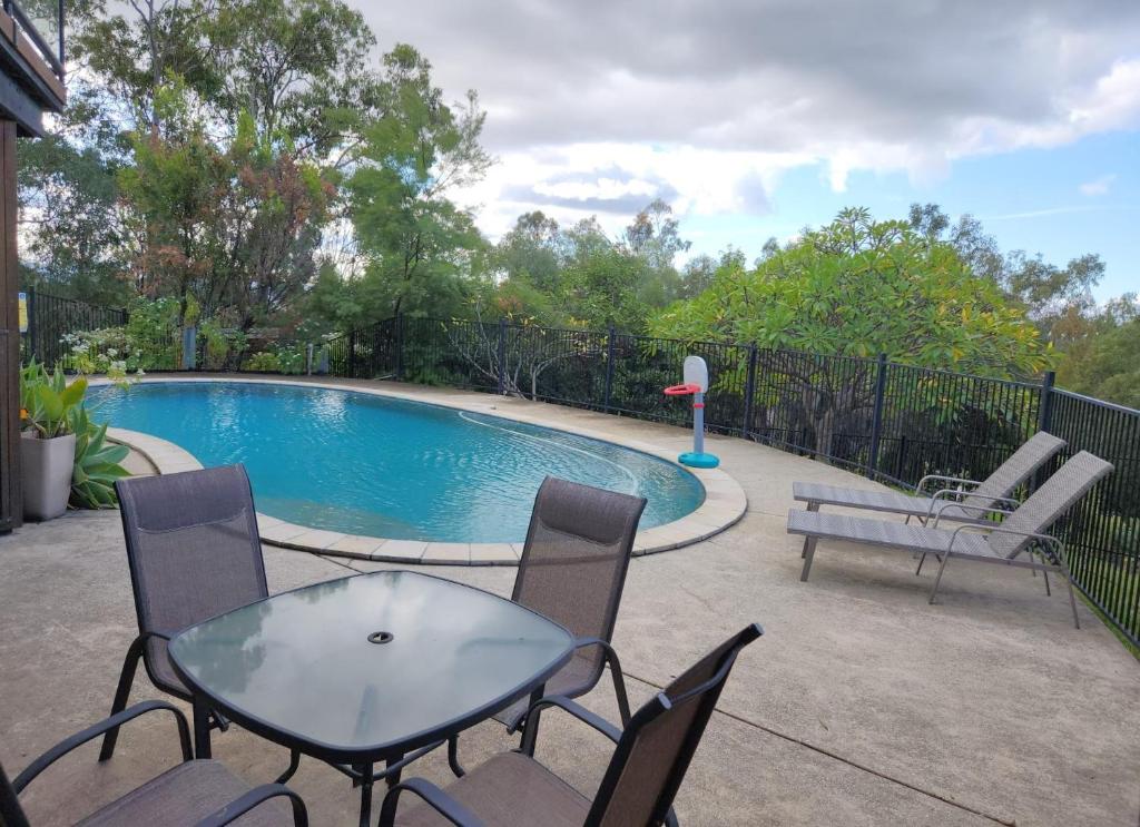 patio ze stołem i krzesłami oraz basenem w obiekcie Self Contained Guesthouse for 7ppl, w Pool w mieście Gold Coast