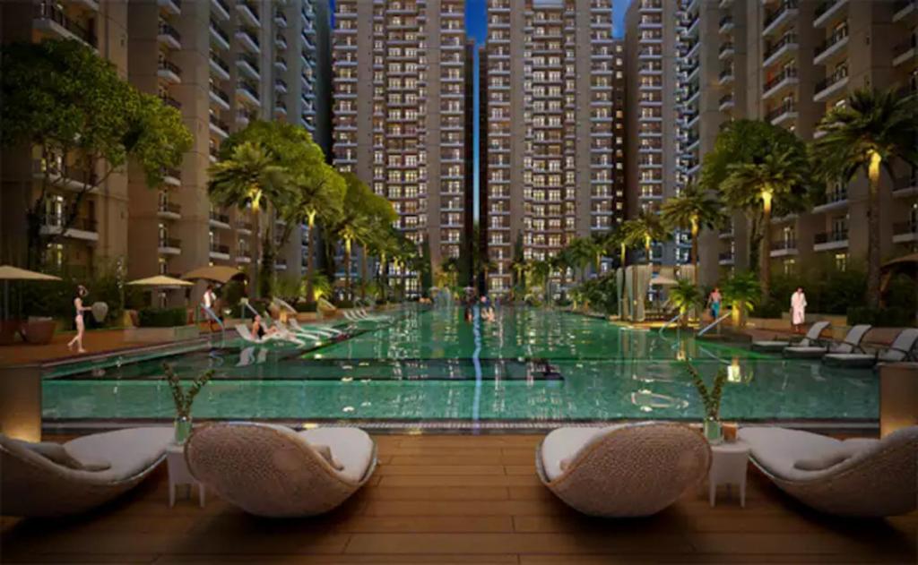 a large swimming pool with chairs and palm trees and buildings at Downtown Delight With Swimming Pool in Lucknow