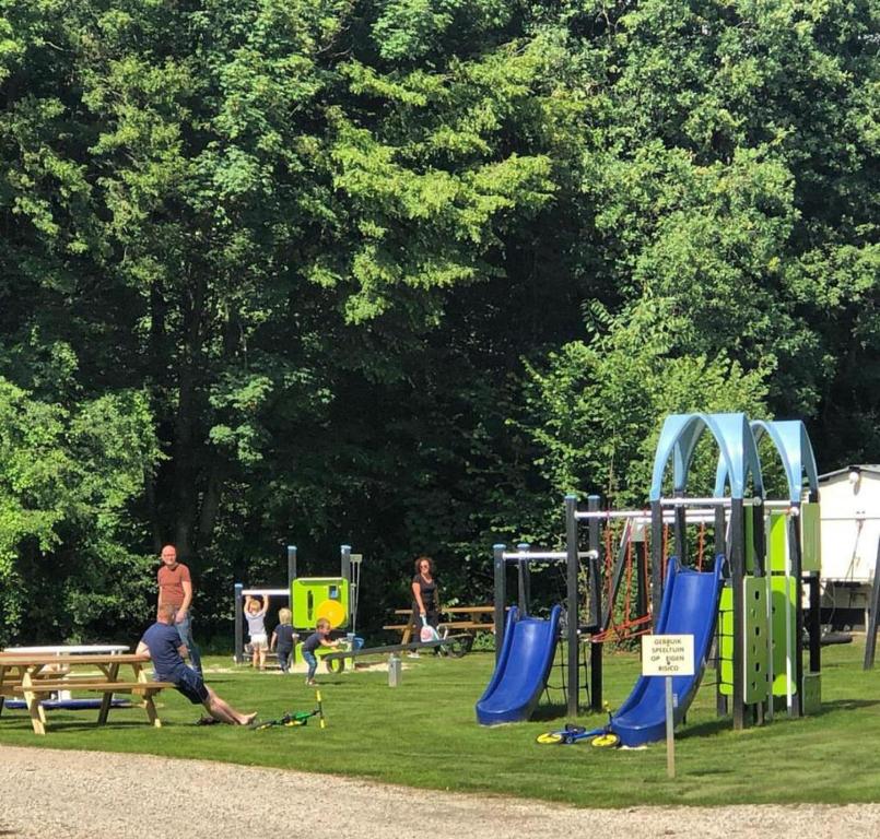a park with people playing on a playground at Camping de Boskant in Guelle