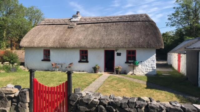 a small white house with a thatched roof at Dream Cottage in Ballintober
